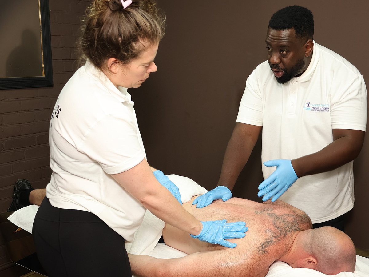 Tutor demonstrating a sports massage technique to a learner